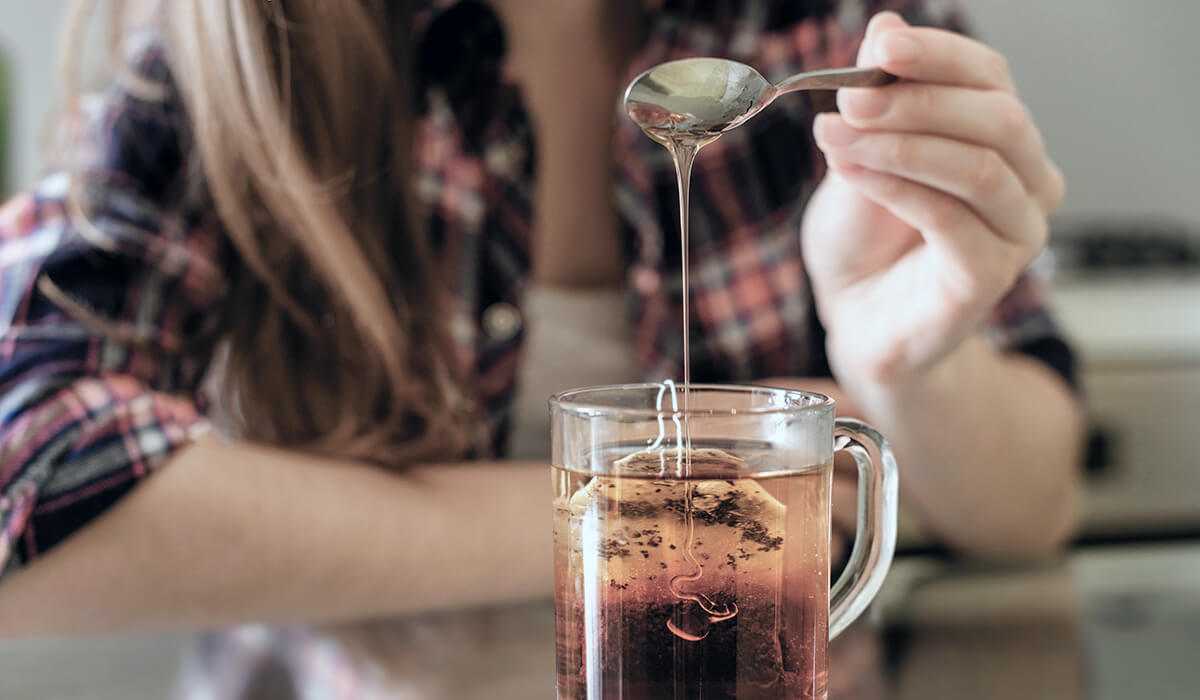 woman drinks tea with honey to soothe her throat that hurts from one of the common respiratory illnesses