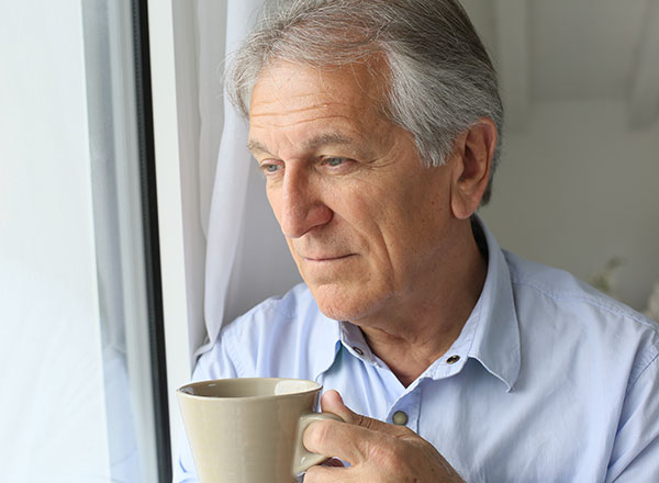 Man with coffee looking out window